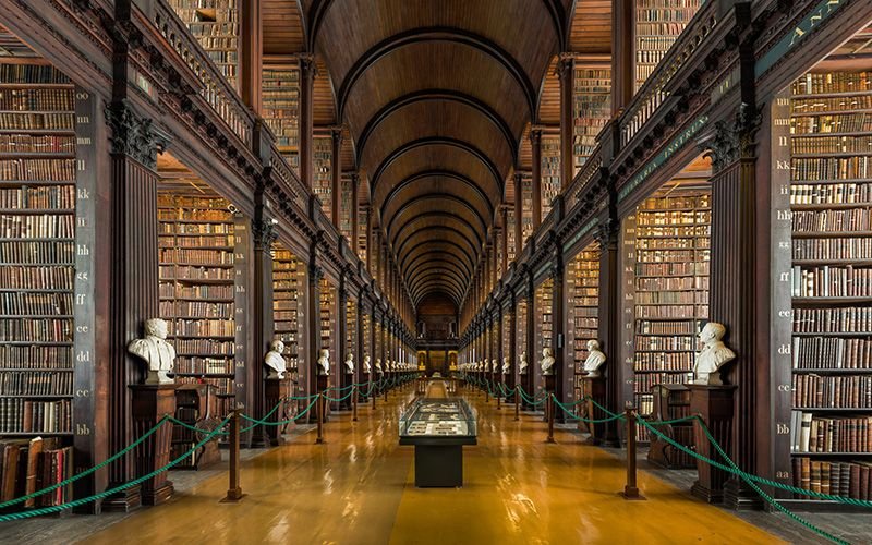 A large, long hall way with different statues of people, and books, in Book Of Kells, Dublin