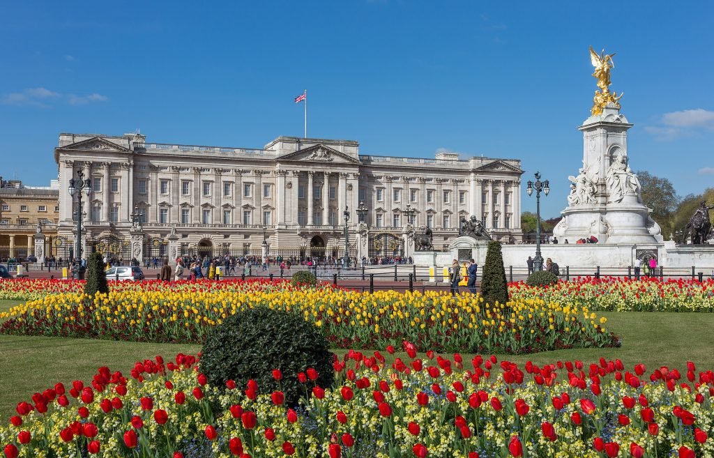 Beautiful red and yellow flowers in front of Buckingham Palace, England with people