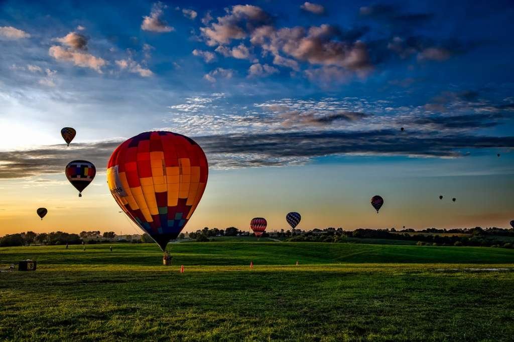 Hot Air Balloons flying in the sky over a large green land
