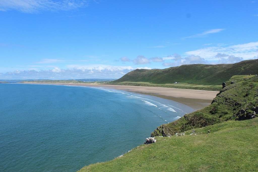 A large beach called Rhossili Bay, in the United Kingdom shows a vast expanse of highlands.