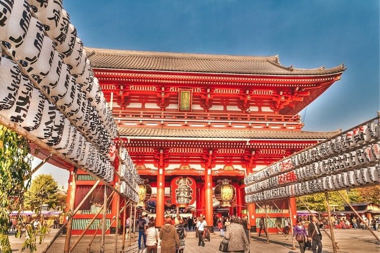 A red and white painted large temple in Tokyo, Japan with lots of Tourists walking around the building