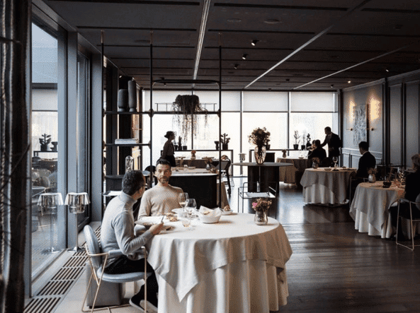 people in a restaurant with chairs and white tables