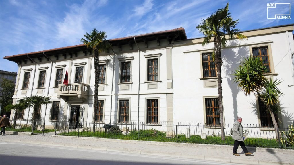 a man walking by a white building in one of the recommended attractions in Vlore, Albania