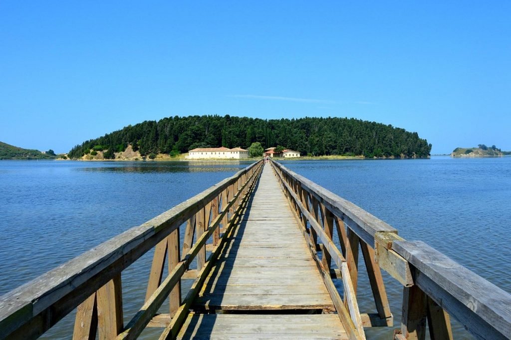 a brown wooden bridge under a blue ocean in one of the recommended attractions in Vlore, Albania