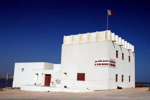 a white and red building under a blue sky in must-visit tourist sites in Al Khor, Qatar.