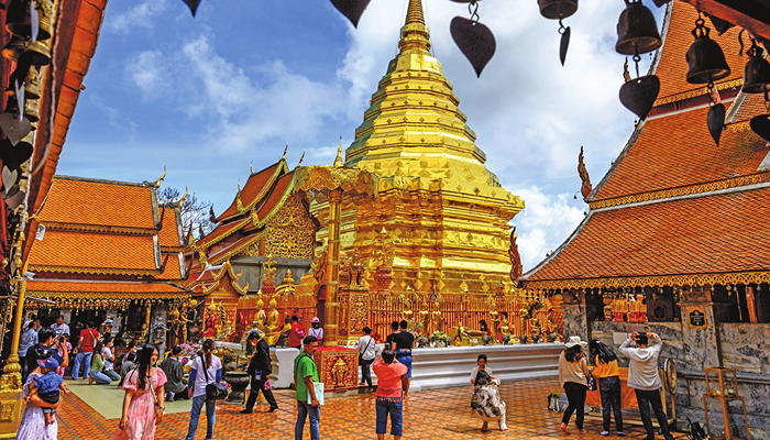 A very beautiful scene in Thailand. Tourists taking pictures and walking around Yellow painted Temples or houses