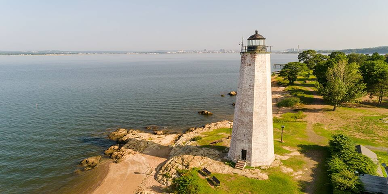 Lighthouse Point Park Beach in New Haven showing a old white painted Lighthouse facing the body of water