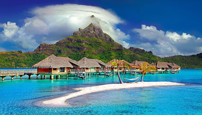 Bora Bora Beach View, French Polynesia. Little huts in front of the clear beach and a huge moutainous terrain in the background