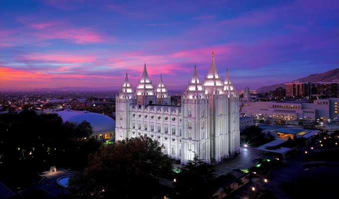 Places to Visit in Salt Lake City, Utah, USA

A white house with bright lights in a large city, surrounded by trees and other buildings, over sunset.