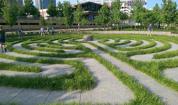 A beautiful garden with well trimmed mat grasses and people walking around
