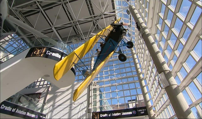 An aviation Museum made with glass walls with a yellow plane hanging at the top
